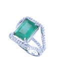 A lady's natural emerald ring with side view of top to three rows of diamond profile.