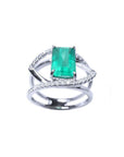 Emerald-cut emerald ring in 14K white gold with split shank and double row of diamonds.