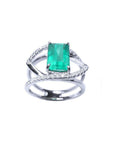 Emerald-cut emerald ring in 14K white gold with split shank and double row of diamonds.