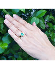 Emerald-cut emerald solitaire ring, bezel set in high-polish 14K gold, worn on a hand.