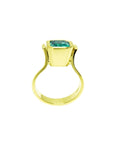 The lateral position of this yellow gold emerald solitaire ring shows the top setting and ring band.
