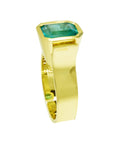 The side profile of this bezel set emerald solitaire ring shows te top and band.