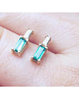 Minimalist 14K gold stud earrings with baguette emeralds and tapered baguette diamonds.