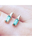 Minimalist 14K gold stud earrings with baguette emeralds and tapered baguette diamonds.