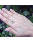 Minimalist 14K gold stud earrings with baguette emeralds and accent diamonds on a hand.