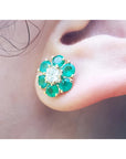 18K yellow gold Colombian emerald and diamond cluster earring on an ear.