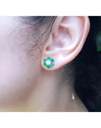 18K yellow gold flower cluster earring with Colombian emeralds and a diamond center on an ear.