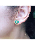 18K yellow gold flower cluster earring with Colombian emeralds and a diamond center on an ear.