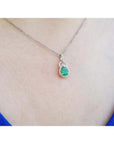 Pear-shaped Colombian emerald and diamond halo pendant in 14K white gold on a silver chain.