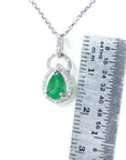 Pear-shaped natural Colombian emerald and diamond halo pendant in 14K white gold, shown with a ruler.