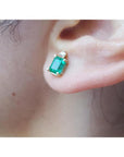 Colombian emerald and diamond stud earring in 14K yellow gold, worn on an ear.