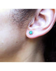 Emerald and diamond tulip stud earring in 14K white gold worn on an ear.