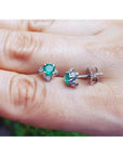 Emerald and diamond tulip stud earrings in 14K white gold, featuring deep bluish-green emeralds and accent diamonds.