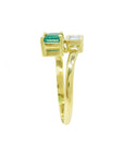 A 18k yellow gold ring featuring a rectangular emerald-cut gemstone on one side and a princess cut diamond on the other.