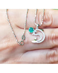 14K white gold dolphin pendant necklace with a round emerald and diamond accents.