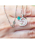 14K white gold dolphin pendant necklace with a round emerald and diamond accents.