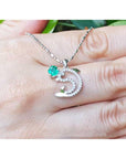 A 14K Solid white gold emerald dolphin pendant on a hand.