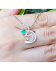 14K white gold dolphin pendant necklace with a round emerald and brilliant diamond accents.