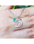 14K white gold dolphin pendant necklace with a round emerald and brilliant diamond accents.