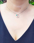 A woman wearing a Colombian emerald dolphin pendants pendant on a blue top.