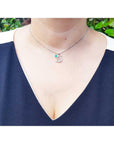 A woman wearing a Colombian emerald dolphin pendants pendant on a blue top.