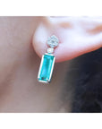 A cluster diamond and a dangle emerald earring made of 14k white gold.