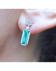 A cluster diamond and a dangle emerald earring made of 14k white gold.