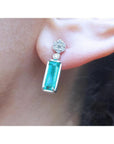 A cluster diamond and a dangle emerald earring made of 14k white gold.