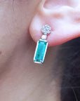 Emerald baguette cut earring worn on an ear with a blurred background