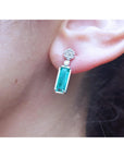 Emerald baguette cut earring worn on an ear with a blurred background