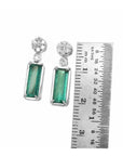 14K white gold dangling earrings with rectangular emeralds and diamond clusters, shown with a ruler.