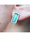 Emerald gemstone earring halo diamond yellow gold worn on a person's ear