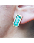 Emerald gemstone earring halo diamond yellow gold worn on a person's ear