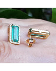 Gold earrings with green emeralds gemstones on a hand