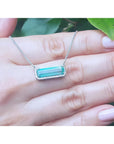 18K white gold necklace with a rectangular Colombian emerald and halo diamonds in an East-West design.