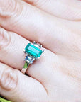 Green gemstone ring on a finger with a blurred background