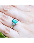 Green gemstone ring on a finger with a blurred background