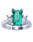 An emerald three stone engagement ring displaying plain top view profile.