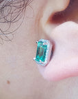 Close-up of an emerald earring left side profile on a person's ear.