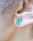 Close-up of an ear wearing a green emerald earring.