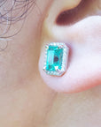 Close-up of an ear wearing a real Colombian emerald stud earring with a diamond halo.