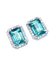 Pair of emerald-cut 14k gold Colombian emerald stud earrings with halo diamond on a right-side position top view.
