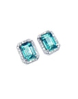 Emerald-cut natural Colombian emerald stud earrings with a halo of diamonds in 14K white gold.