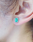 Close-up of an ear wearing a Colombian emerald earring with a white gold setting.