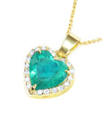Gold necklace with a heart-shaped emerald pendant with diamonds on a side profile view.