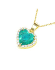 Gold necklace with a heart-shaped emerald pendant with diamonds on a side profile view.