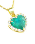 Gold necklace with a heart-shaped emerald pendant with a halo diamond on a topside view position.