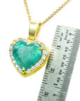 Gold pendant with a heart-shaped natural emerald and diamonds, next to a ruler for scale.