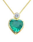Heart-shaped emerald pendant with gold frame and diamond on a topside view.
