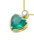 Gold pendant with a heart-shaped emerald and small diamond on top, lef-side profile view.